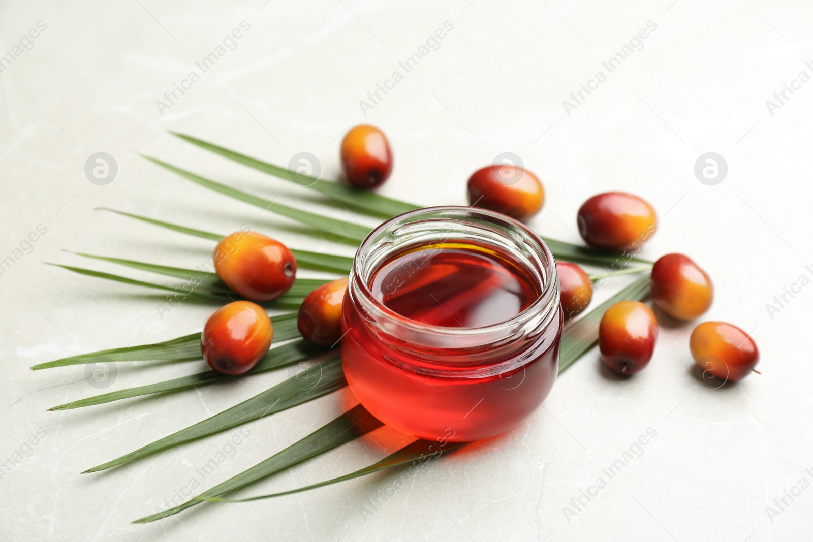 Image of Palm oil in glass jar, tropical leaf and fruits on light table