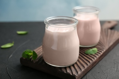 Photo of Jars with yummy yogurt on wooden board