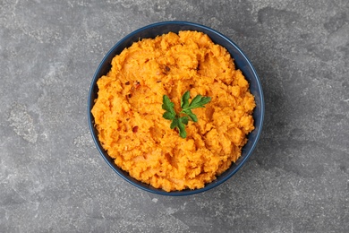 Photo of Bowl with mashed sweet potatoes on grey background, top view