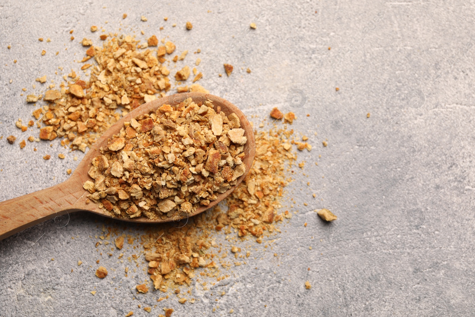 Photo of Spoon with dried orange zest seasoning on light grey table, top view. Space for text