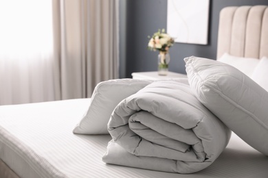 Photo of Soft folded blanket and pillows on bed indoors