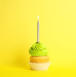 Birthday cupcake with candle on yellow background