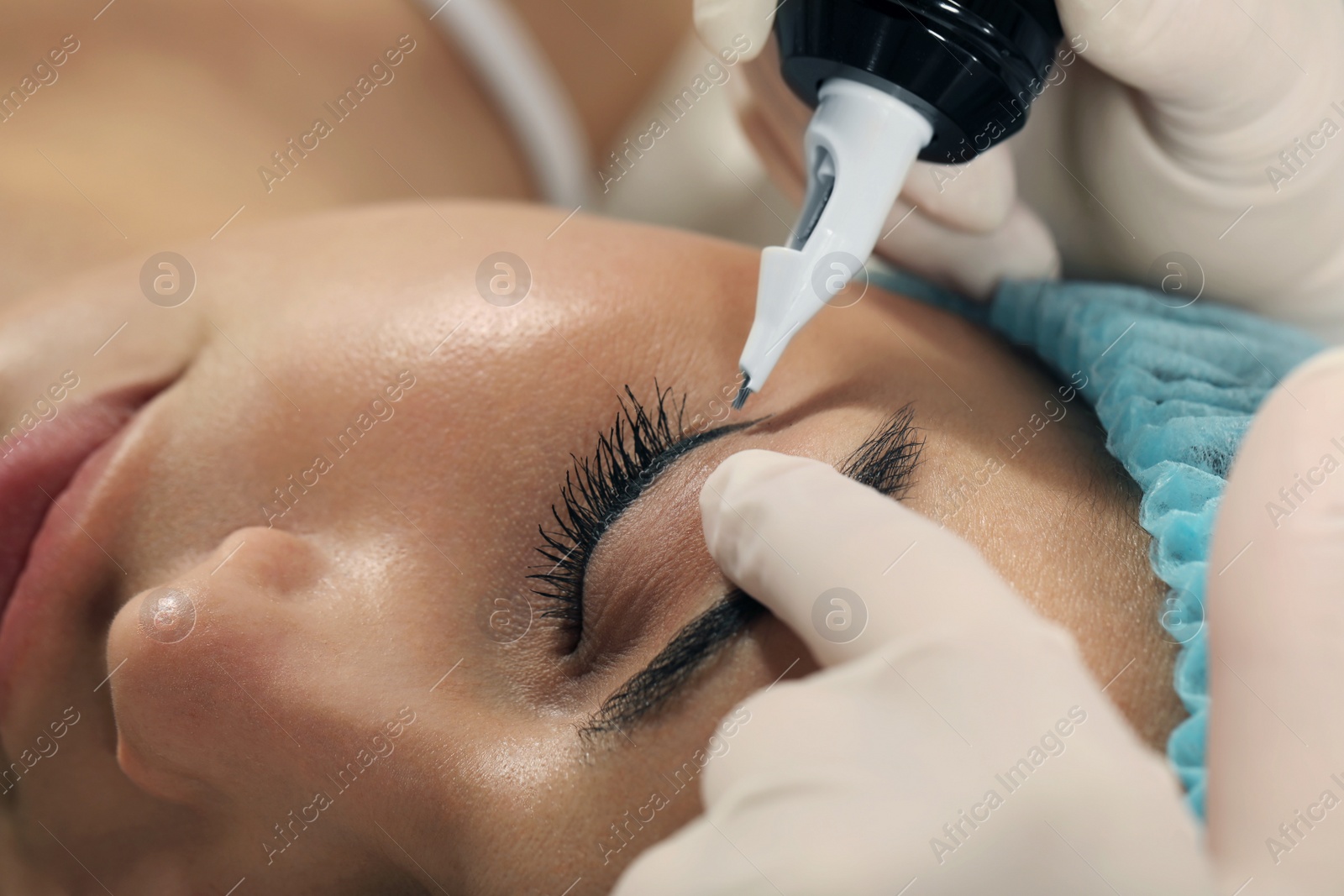 Photo of Young woman undergoing procedure of permanent eyeliner makeup, closeup