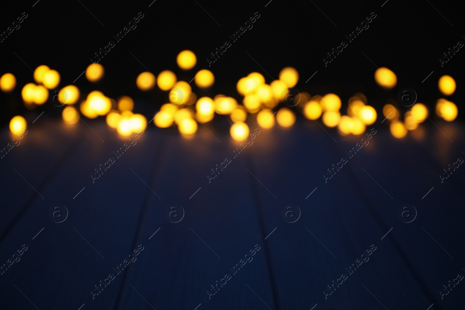 Photo of Blurred view of beautiful glowing lights, focus on blue wooden table. Space for text