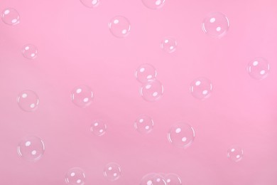 Many beautiful soap bubbles on pink background