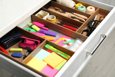 Photo of Stationery and sewing accessories in open desk drawer indoors