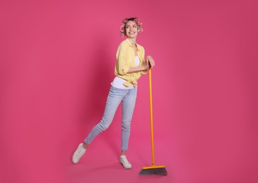 Photo of Young housewife with broom on pink background