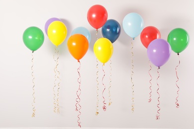 Photo of Different bright balloons on light background. Celebration time