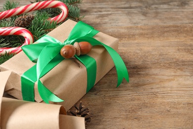 Photo of Christmas gift box with green ribbon and acorns on wooden table