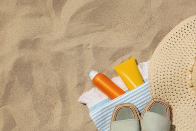 Flat lay composition with sunscreens on sand, space for text. Sun protection care