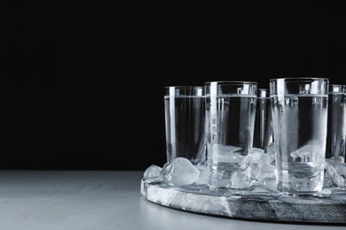 Vodka in shot glasses and ice on grey table. Space for text