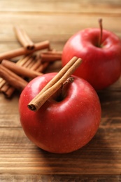 Photo of Fresh apples and cinnamon sticks on wooden table
