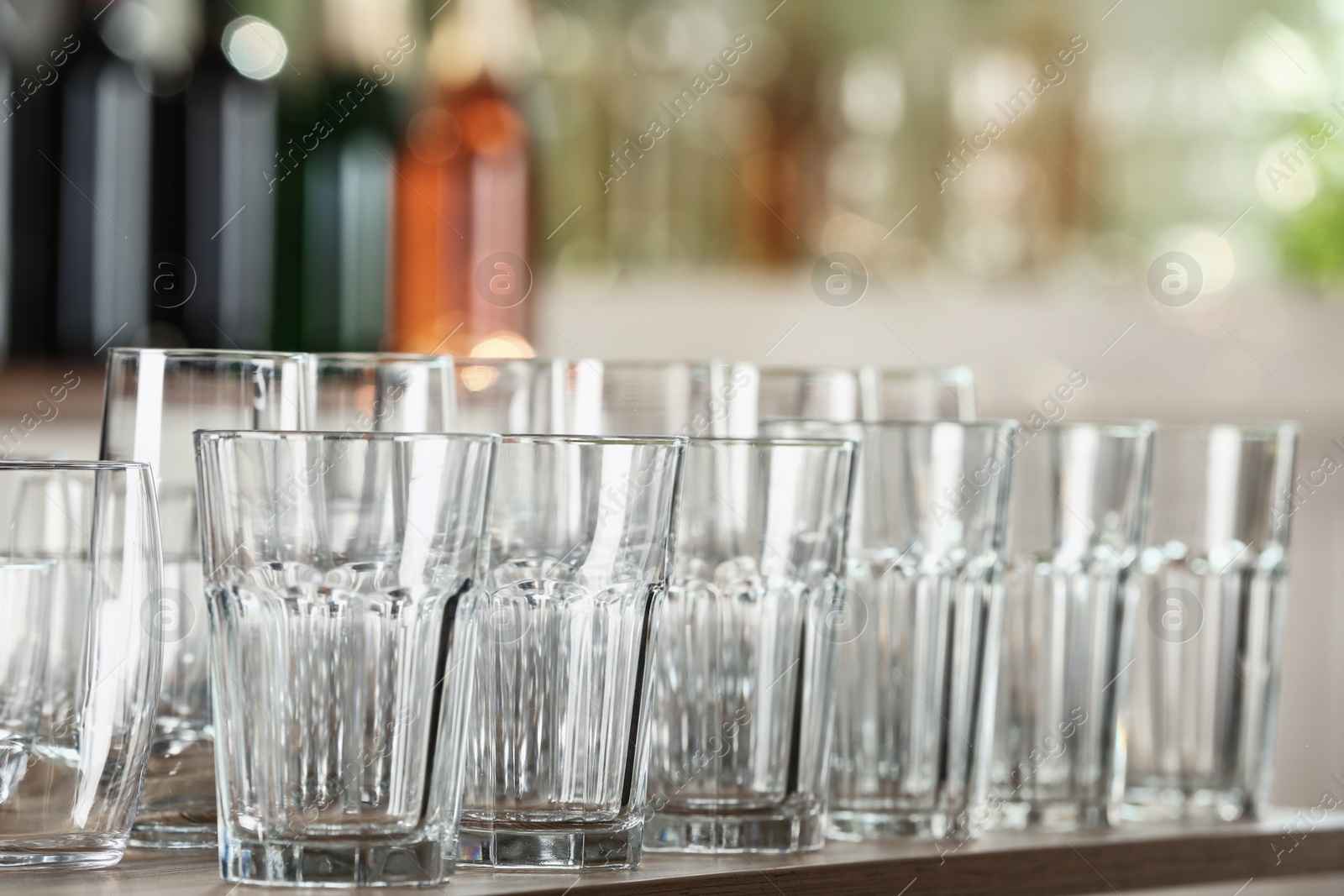 Photo of Empty glasses on wooden table against blurred background