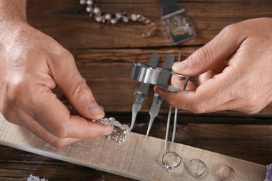 Photo of Male jeweler evaluating diamond bracelet in workshop, closeup view