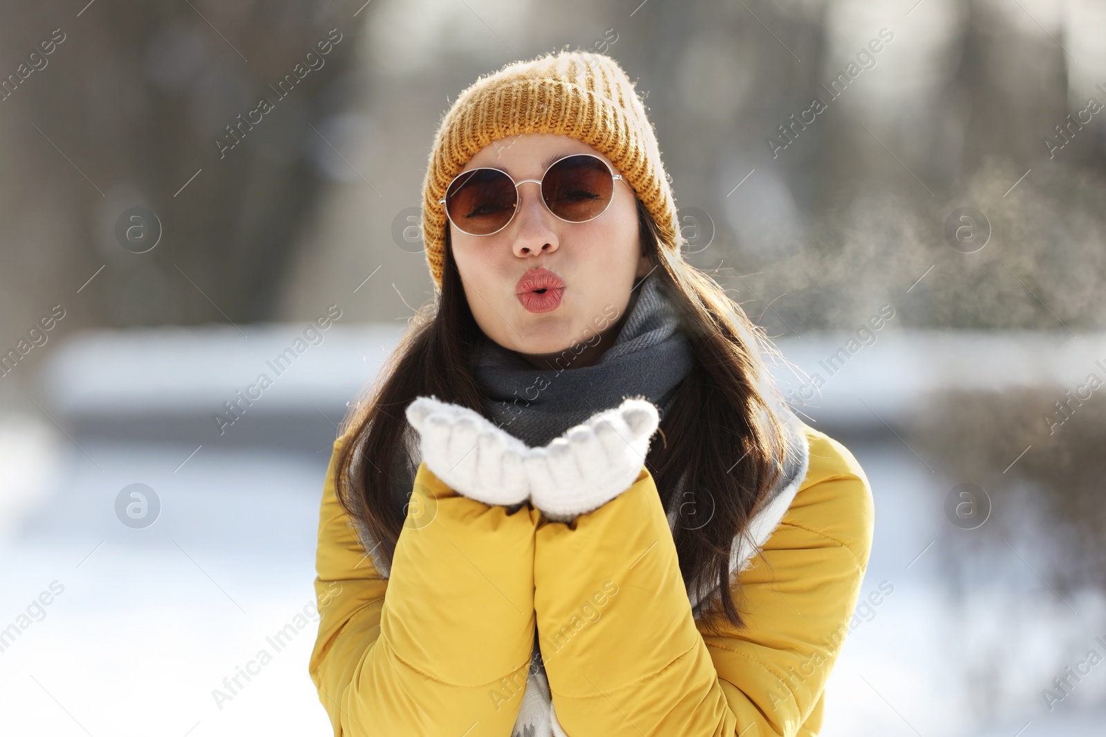 Photo of Beautiful young woman with sunglasses blowing kiss on winter day outdoors