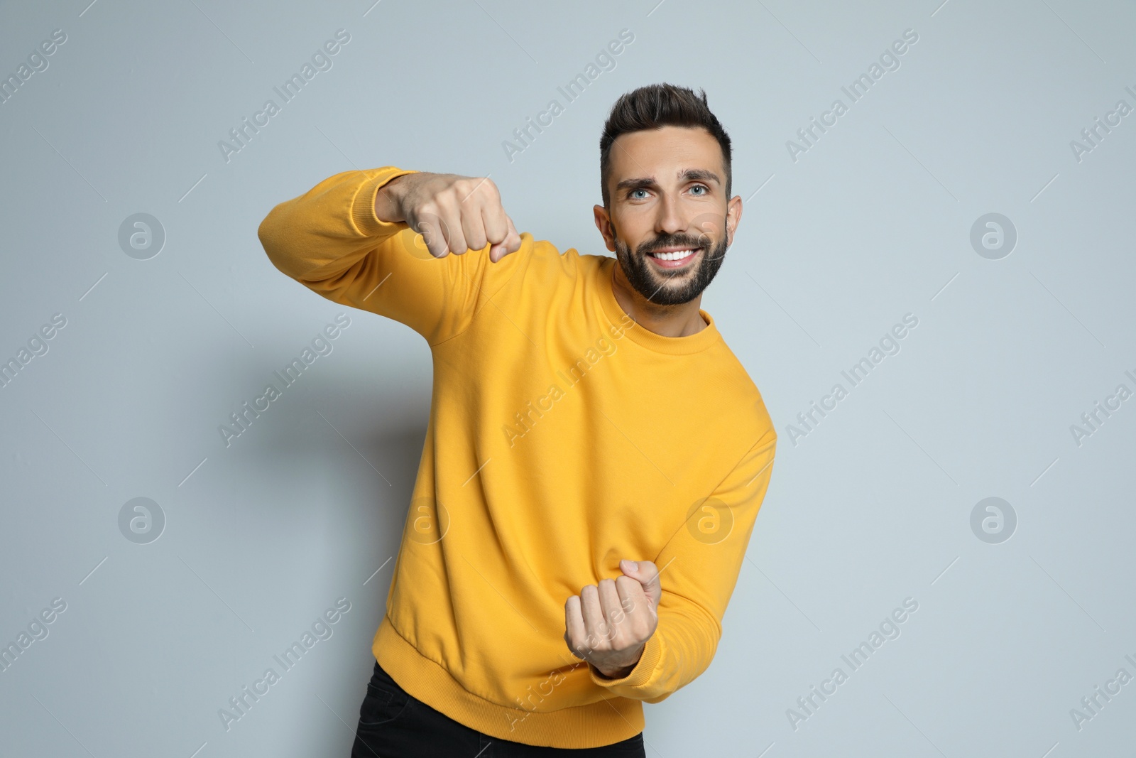 Photo of Happy man pretending to drive car on grey background