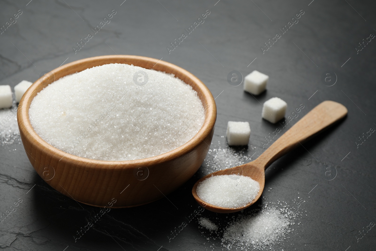 Photo of Granulated sugar in bowl on dark table