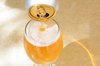 Pouring beer from can into glass on table, closeup. Space for text