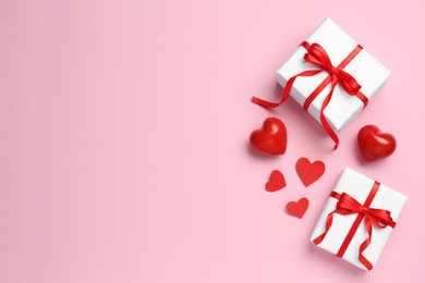 Photo of Beautiful gift boxes and red decorative hearts on pink background, flat lay. Space for text