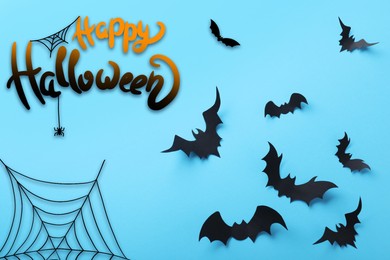 Image of Happy Halloween. Paper bats on light blue background, flat lay