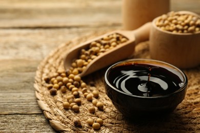 Soy sauce in bowl and beans on wooden table, closeup. Space for text