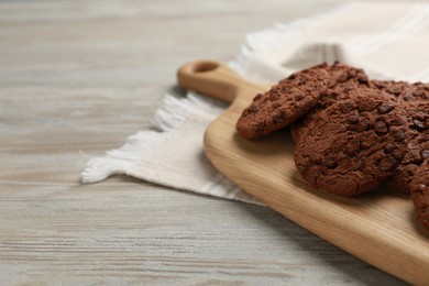 Photo of Delicious chocolate chip cookies on light wooden table, closeup. Space for text