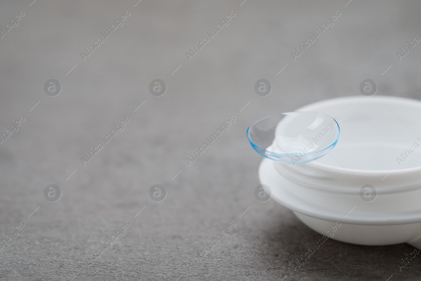 Photo of Case with contact lens on grey table, closeup. Space for text