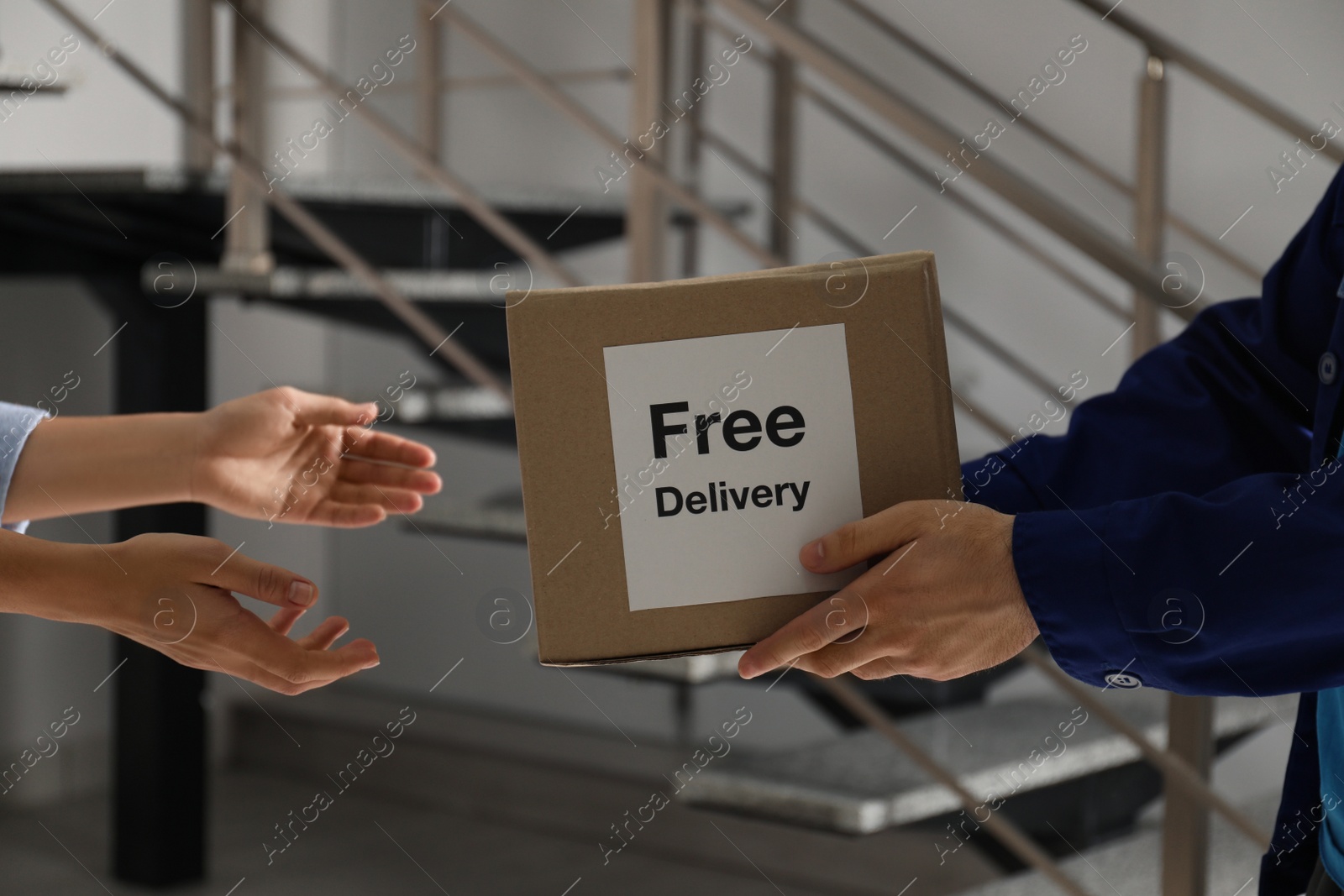 Photo of Woman receiving parcel with sticker Free Delivery from courier indoors, closeup