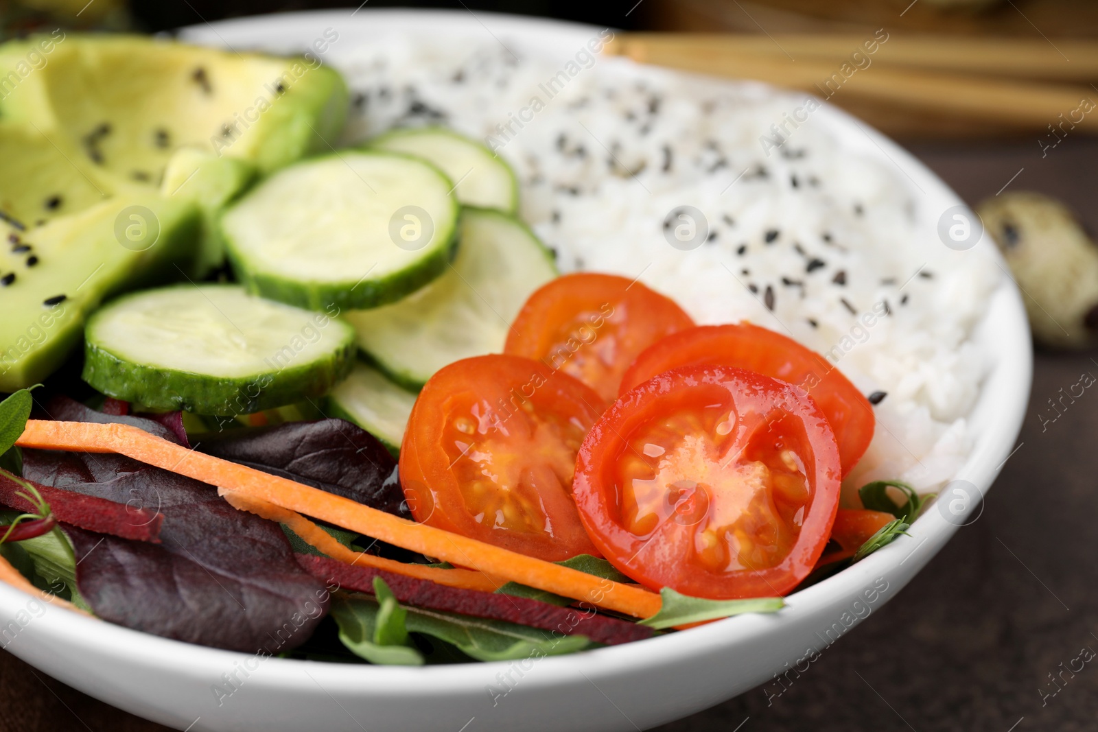 Photo of Delicious poke bowl with vegetables, avocado and mesclun on textured table, closeup