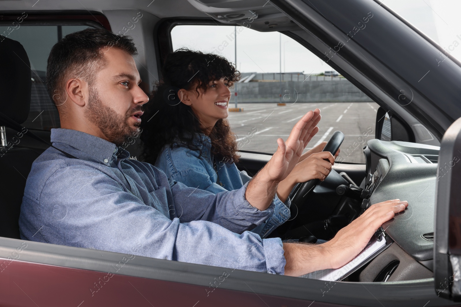 Photo of Driving school. Happy student passing driving test with examiner in car at parking lot