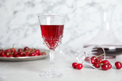 Delicious cherry wine and ripe juicy berries on white table