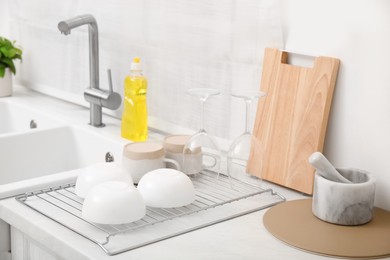 Photo of Drying rack with clean dishes near sink in stylish kitchen