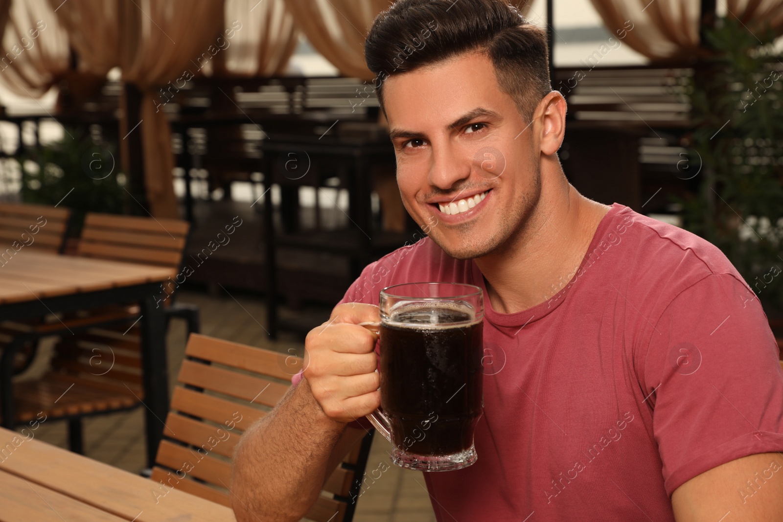 Photo of Man with glass of dark beer in outdoor cafe