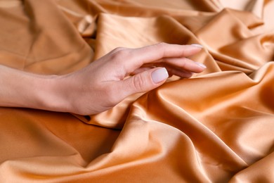 Photo of Woman touching soft orange fabric, closeup view