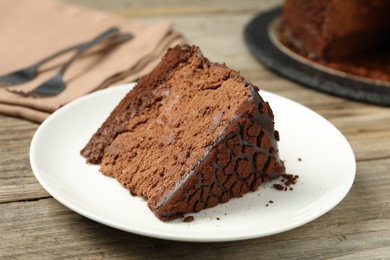 Photo of Piece of delicious chocolate truffle cake on wooden table, closeup