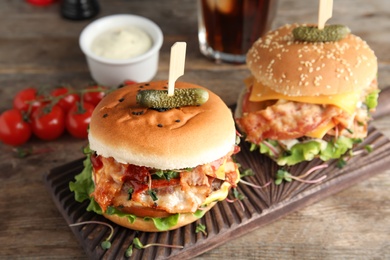 Tasty burgers with bacon served on table