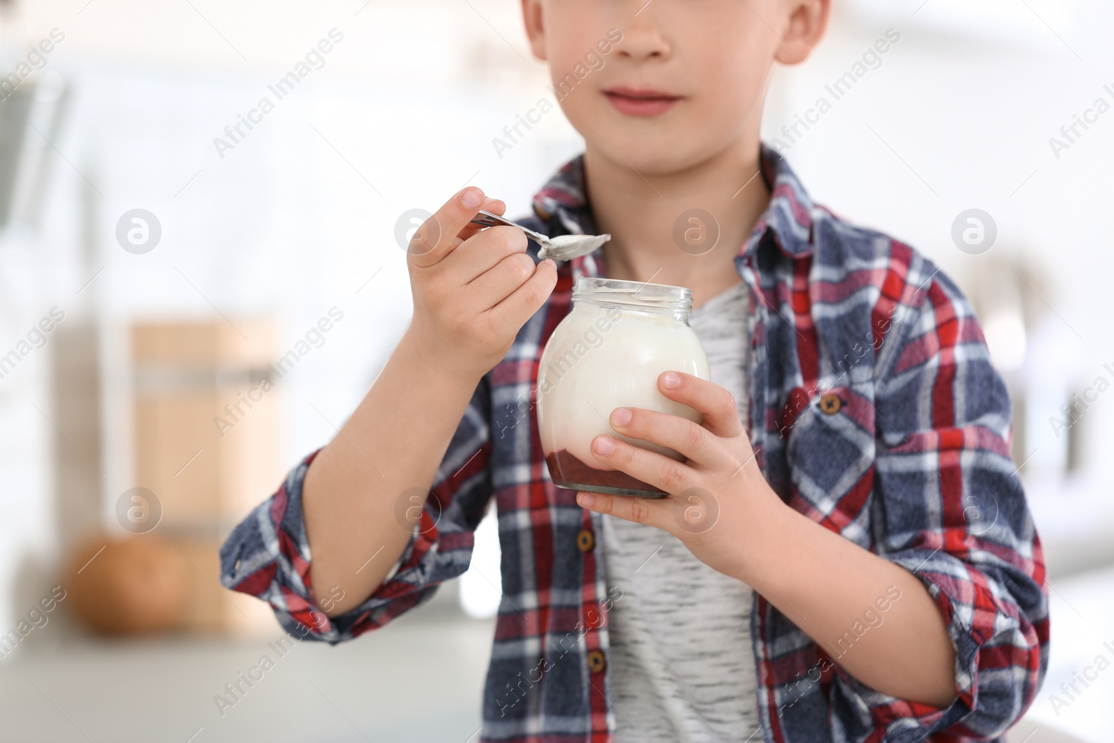 Photo of Little boy with yogurt on blurred background, closeup