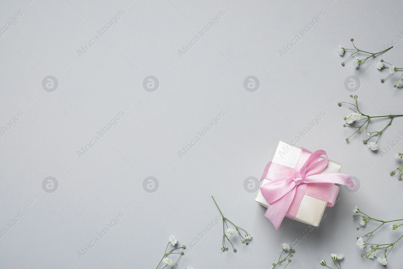 Photo of Gift box and flowers on grey background, space for text. Happy Mother's Day