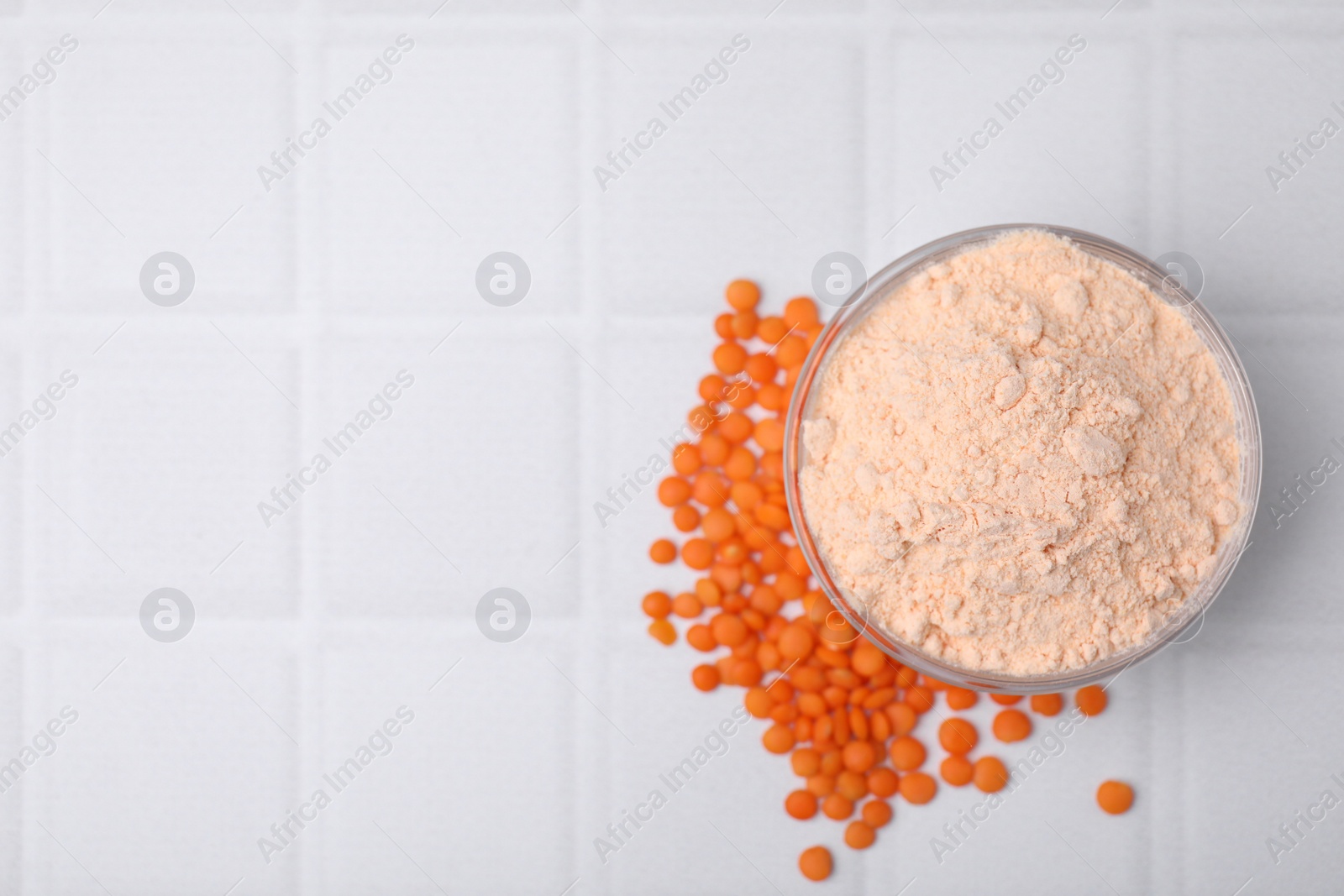 Photo of Bowl of lentil flour and seeds on white tiled table, flat lay. Space for text