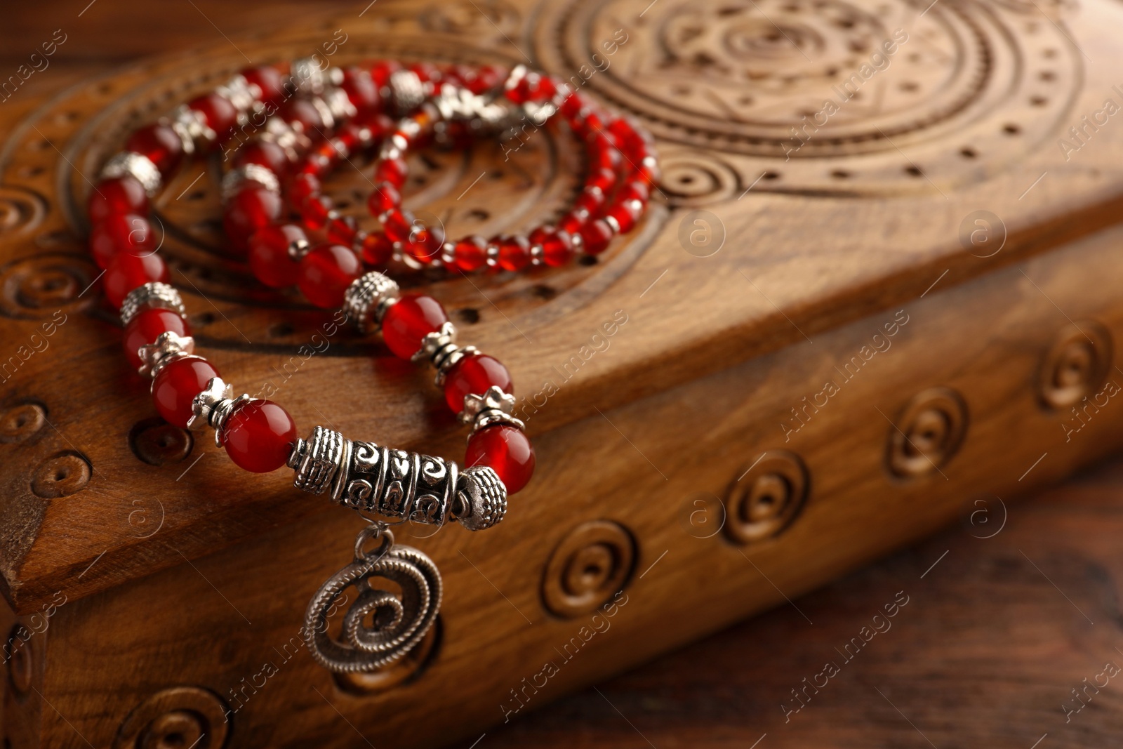 Photo of Beautiful necklace with gemstones and wooden jewelry box on table