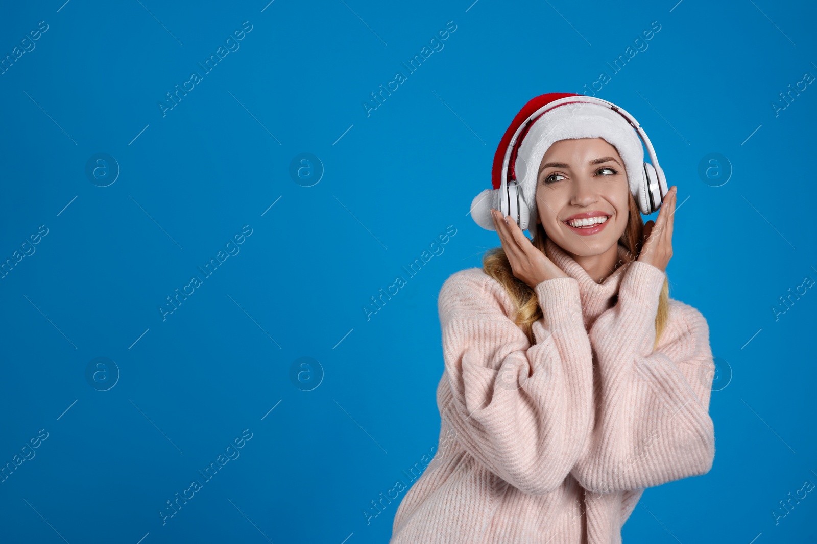 Photo of Happy woman with headphones on blue background, space for text. Christmas music