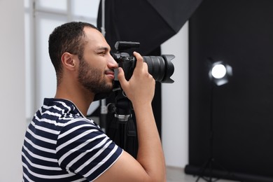 Young professional photographer taking picture in modern photo studio, space for text