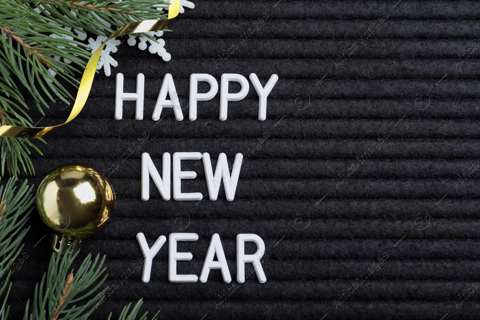 Photo of Happy New Year greeting card. Phrase made with letters and decor on black background, flat lay