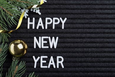 Happy New Year greeting card. Phrase made with letters and decor on black background, flat lay