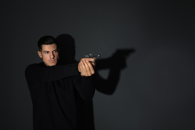 Photo of Professional killer with gun on black background