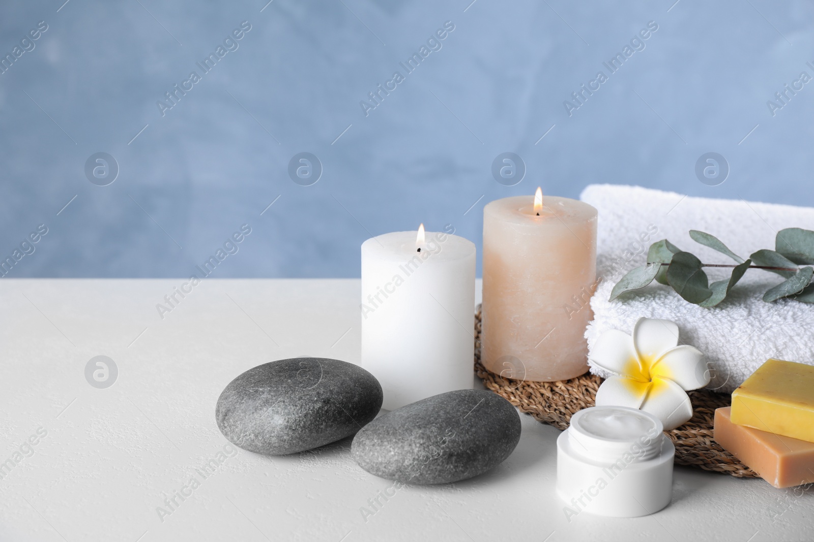 Photo of Composition with cream and burning candles on white table. Spa treatment