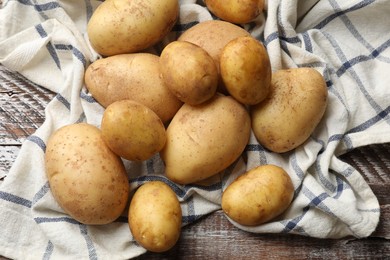 Photo of Raw fresh potatoes and napkin on wooden table, top view