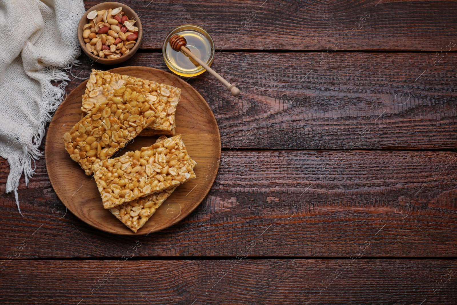 Photo of Delicious peanut bars (kozinaki) and ingredients on wooden table, flat lay. Space for text