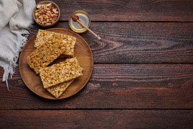 Delicious peanut bars (kozinaki) and ingredients on wooden table, flat lay. Space for text