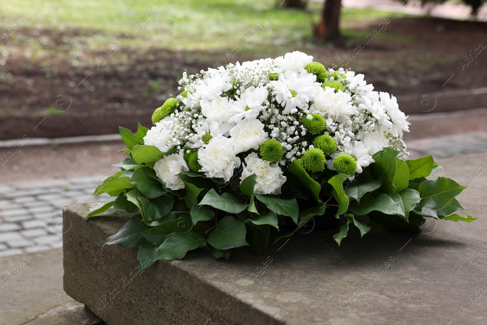 Photo of Funeral wreath of flowers on tombstone outdoors